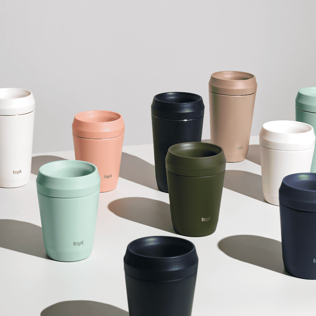 Collection of colorful reusable cups on a light background